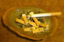 ashtray with lit cigarette & stubs