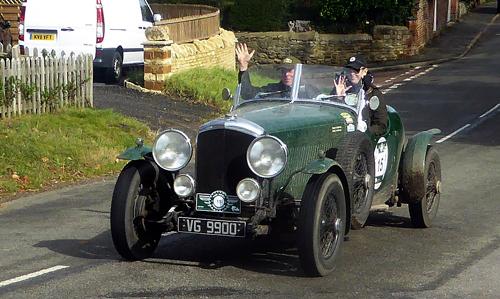 Emily and Stuart Anderson wave as their 4.25 litre Bentley Derby (1937) passes the end of Abthorpe’s Main Street.