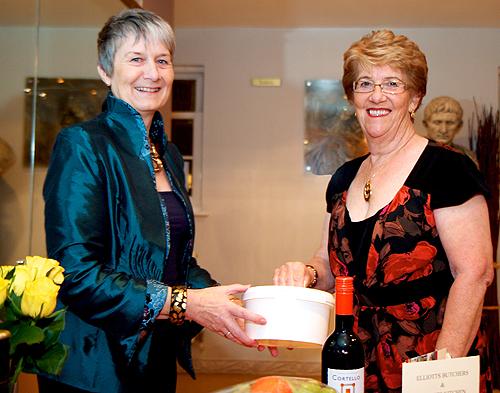 Mary-Jane Willows holds the tin while founding chair Jill Moss makes the draw