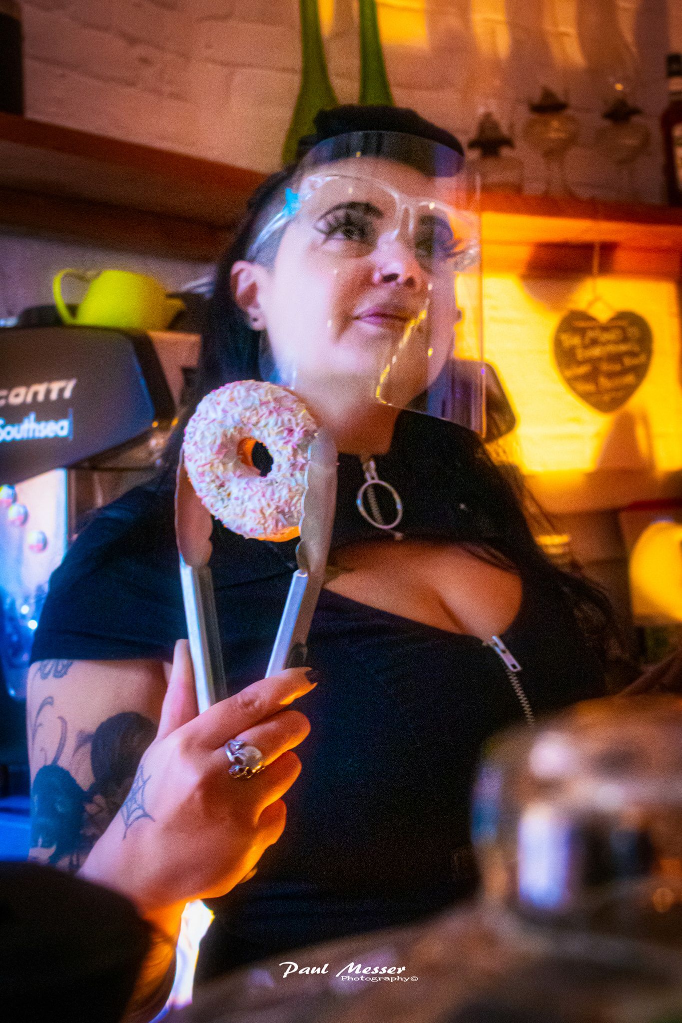Dominique of The Rabbit Hole holding up a donut behind the coffee bar counter