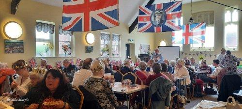 The decorated hall and Welcome Café customers listening to Lay Pastor Len Sloan talking about Kingship and the symbolism in the coronation service.